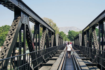 Rear view of woman walking on footbridge