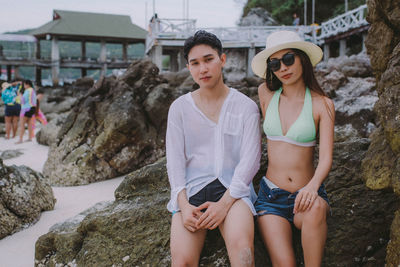 Portrait of couple sitting on rock at beach