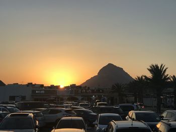 Cars in city against clear sky during sunset