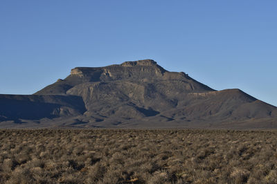 Scenic view of arid landscape against clear blue sky