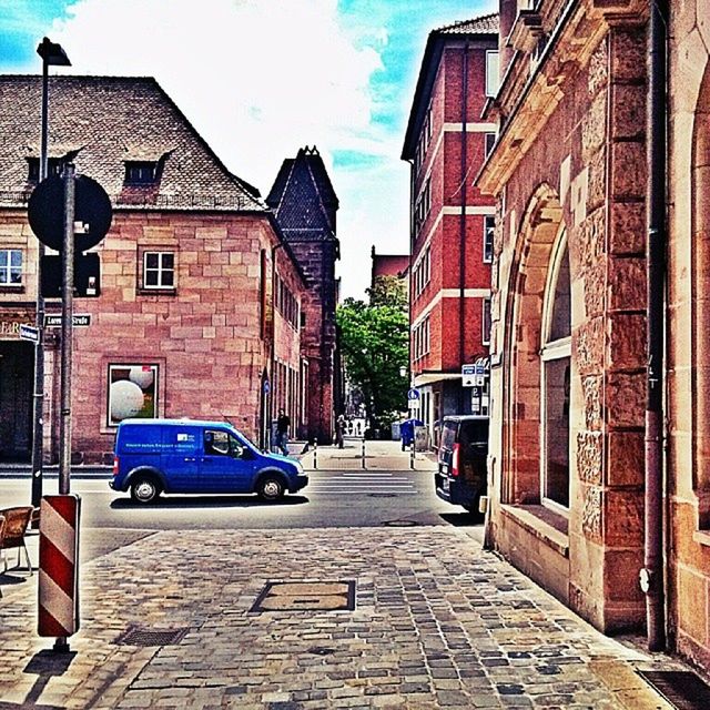 building exterior, architecture, built structure, street, the way forward, city, transportation, building, road, residential building, car, residential structure, sky, cobblestone, sidewalk, land vehicle, day, outdoors, city street, sunlight