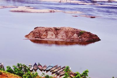 Moored rowboats at beach by rock