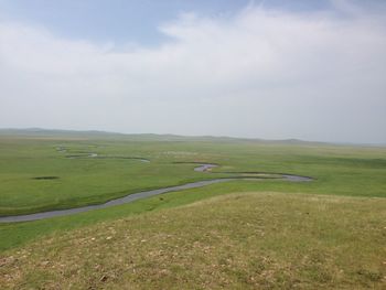 Scenic view of grassy field against sky