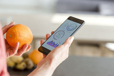 Woman holding smartphone with mobile app and orange