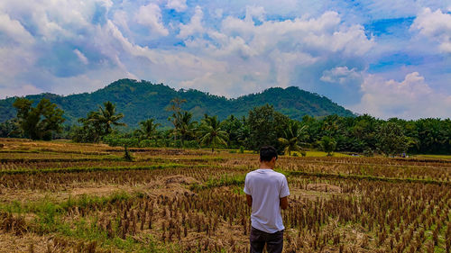 Rear view of man on field against sky