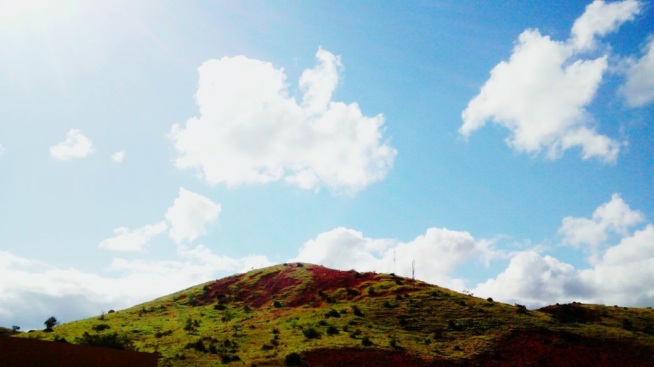 sky, tranquil scene, tranquility, mountain, scenics, beauty in nature, cloud - sky, nature, cloud, blue, low angle view, landscape, idyllic, cloudy, day, non-urban scene, mountain range, outdoors, sunlight, remote