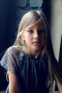Fashionable little girl sitting on window in grey dress