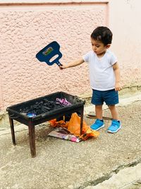 Baby boy playing by fire pit against wall on footpath