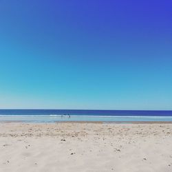 Scenic view of calm beach against blue sky