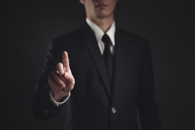 Midsection of man standing against black background