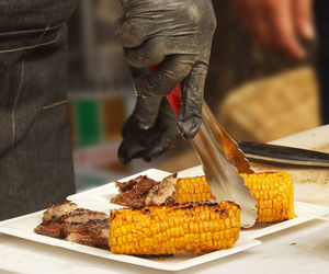 Close-up of person preparing food on barbecue grill