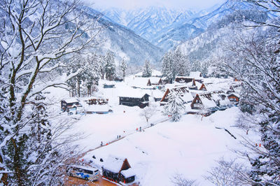 High angle view of snow covered houses and trees by mountains