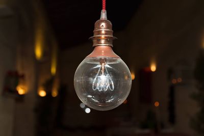 Close-up of light bulb hanging at night