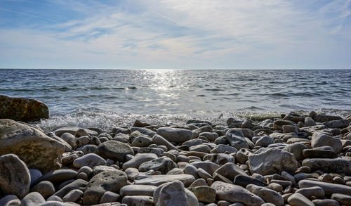 Scenic view of rocks by sea against sky