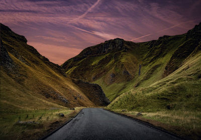 Country road amidst landscape against sky