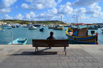 Rear view of man at harbor against sky