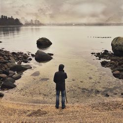 Rear view of man standing on rock against sea