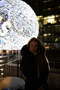 Portrait of a smiling young woman standing at night