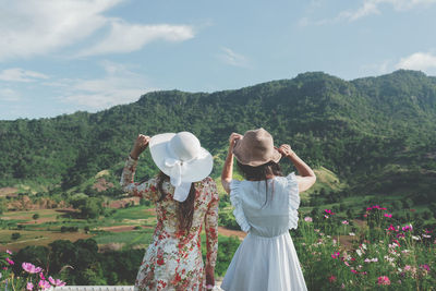 Rear view of female friends standing against mountains