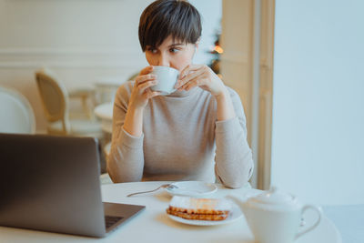 Woman drinking coffee while sitting in cafe
