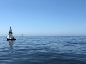 Sailboat sailing in sea against clear blue sky