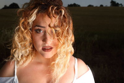 Portrait of young woman with curly hair on field at night