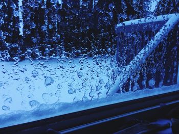 Close-up of wet car window against sky