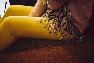 Midsection of woman sitting on sofa at coffee shop