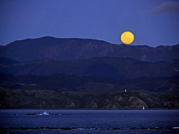 Scenic view of moon over mountains against sky at night