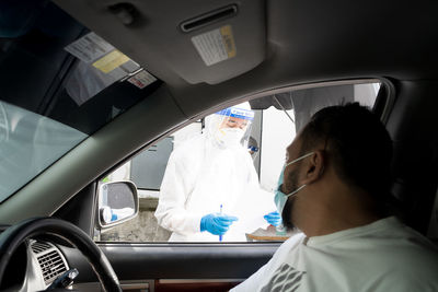 Healthcare worker is performing a pcr swab test by drive thru lab.