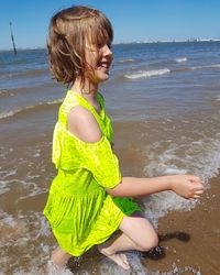 Happy girl standing on beach against sea