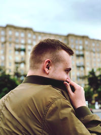 Close-up of young man wearing warm clothing against building