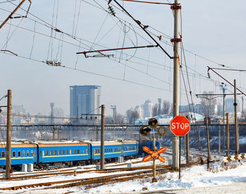 A red stop sign at a railroad crossing against the backdrop of railroad tracks, blue train carriages