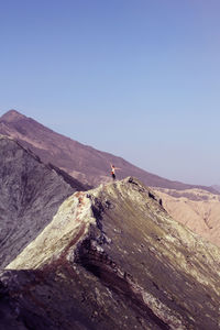 Woman standing on mountain ridge against clear sky