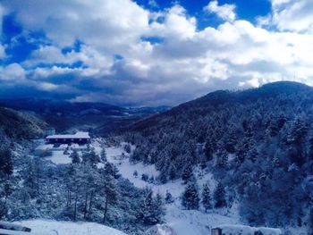 Scenic view of snow covered mountains against cloudy sky