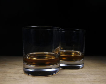 Close-up of beer glass on table against black background