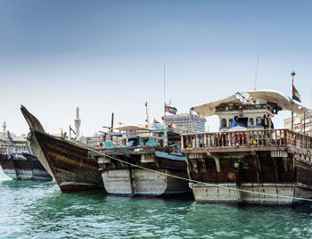 Boats moored at harbor against clear sky