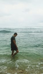 Side view of young woman standing at beach