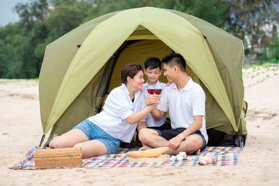 Family spending leisure time under tent at beach