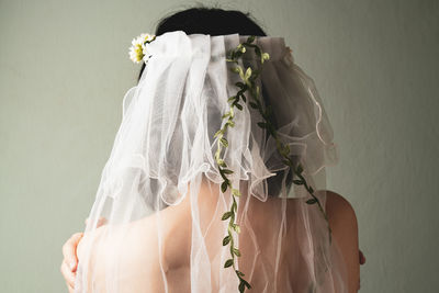 Rear view of bride with veil against wall