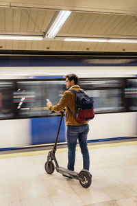 Full length of man with electric push scooter standing on subway station