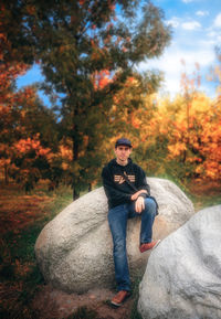 Portrait of man sitting on rock during autumn
