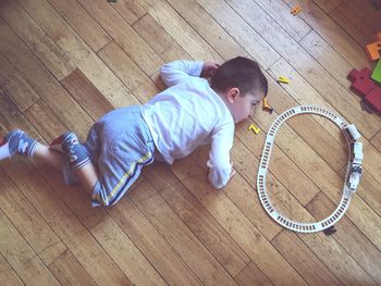 Directly above view of boy playing with toy train on hardwood floor