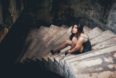 High angle view of young woman sitting on staircase