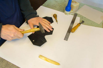 Midsection of man making wallet on table
