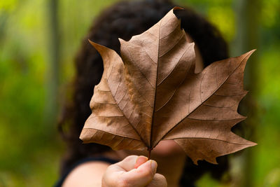 Woman holding leaf in front of face