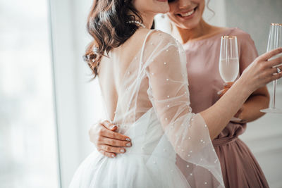 Bridesmaid and bride holding champagne flute