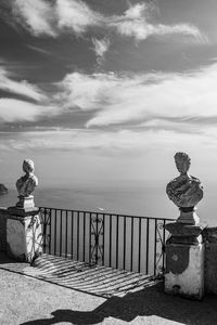 Statue on railing by sea against sky