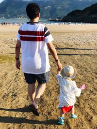 Rear view of father and son walking at beach