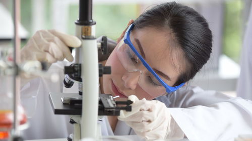 Scientist looking at microscope while sitting in laboratory